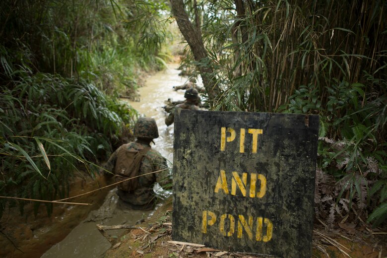 Marines with Communications Company, Headquarters Regiment, 3rd Marine Logistics Group, begin their decent into the muddy water during an obstacle in the Endurance Course on Camp Gonsalves, Okinawa, Japan, Feb. 16, 2018. The "Pit and Pond" is an obstacle in the E-Course made up of low crawls through water-filled trenches and under walkways in the Jungle Warfare Training Center. BJSC is designed to teach Marines how to operate in a jungle environment. (U.S. Marine Corps photo by Lance Cpl. Jamin M. Powell)