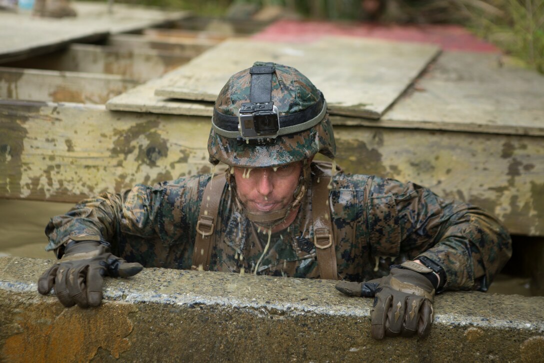 First Sgt. Thomas W. Tabisz, the company first sergeant for Communications Company, Headquarters Regiment, 3rd Marine Logistics Group, lifts himself out of a muddy, water-filled pit during the Endurance Course on Camp Gonsalves, Okinawa, Japan, Feb. 16, 2018. Marines of Comm. Co. participated in the E-Course as the final event of the Basic Jungle Skills Course at the Jungle Warfare Training Center, which teaches Marines how to operate in a jungle environment. Tabisz is a native of Chicago, Illinois. (U.S. Marine Corps photo by Lance Cpl. Jamin M. Powell)