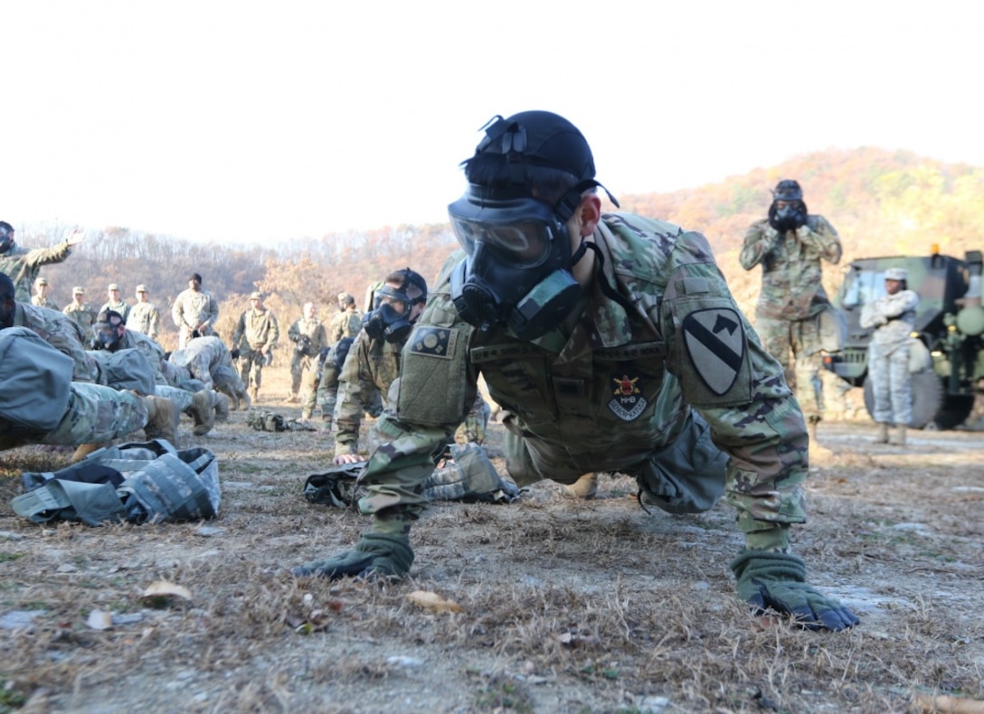 A soldier does pushups in a gas mask.