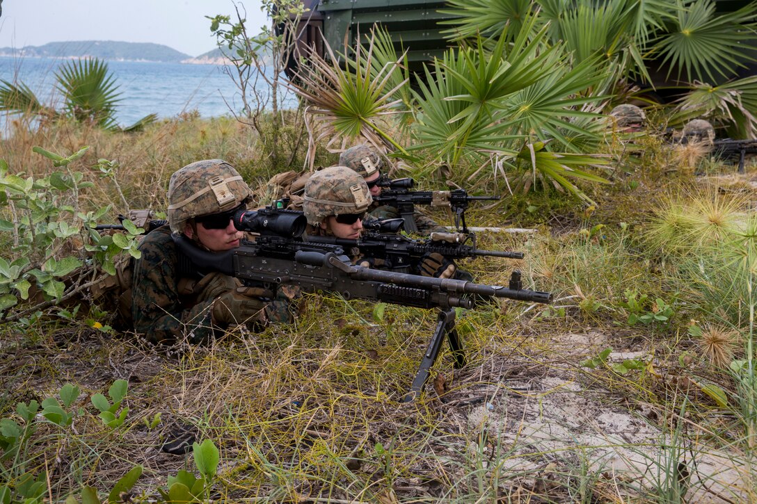 Marines lay on the ground pointing machine guns.