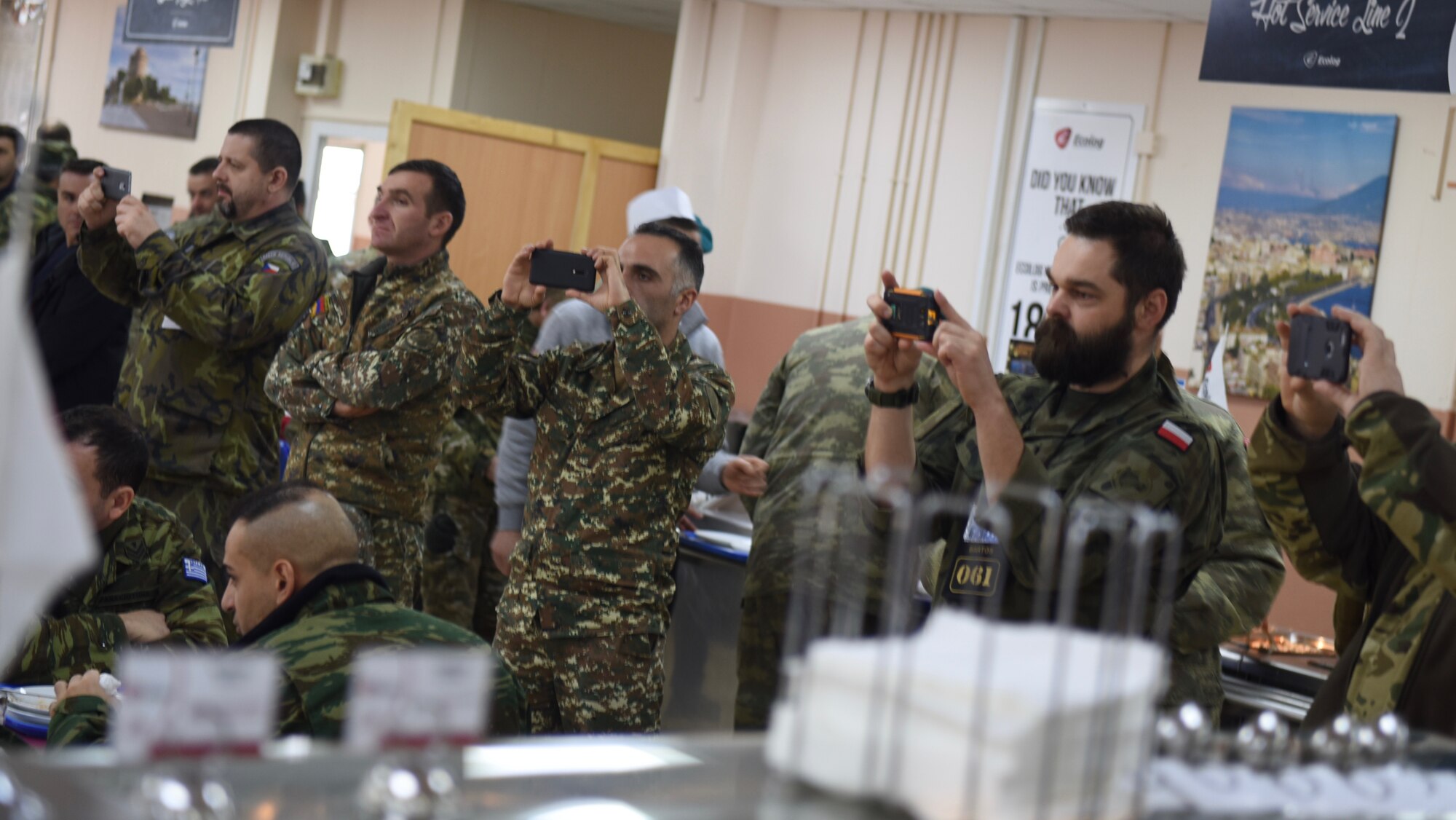 NATO service members with Kosovo Force listen to the U.S. Air Forces in Europe Band perform at the dining facility at Camp Film City, Kosovo, Feb. 15, 2018. The band visited and performed in the country to celebrate the 10th anniversary of Kosovo independence. (U.S. Air Force photo by Maj. Tristan Hinderliter)