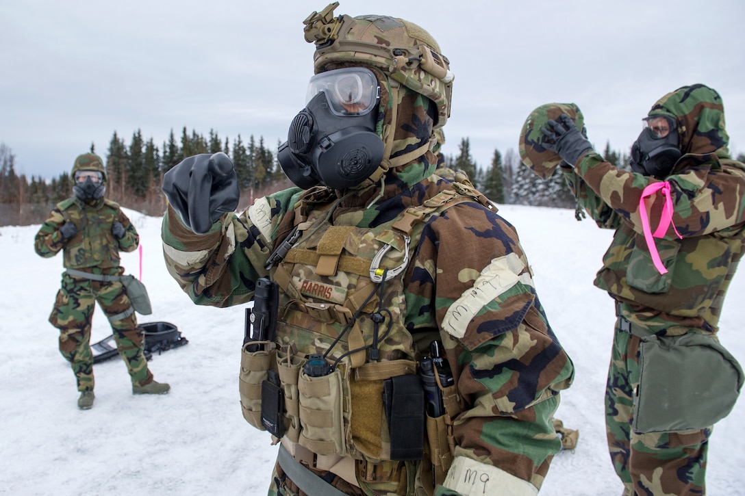 Air Force Staff Sgt. Joshua Harris, foreground, gives instruction to airmen as they don protective gear before a live-fire.
