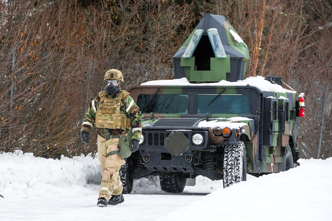 Air Force Senior Master Sgt. Ronald White walks in front of an armored Humvee