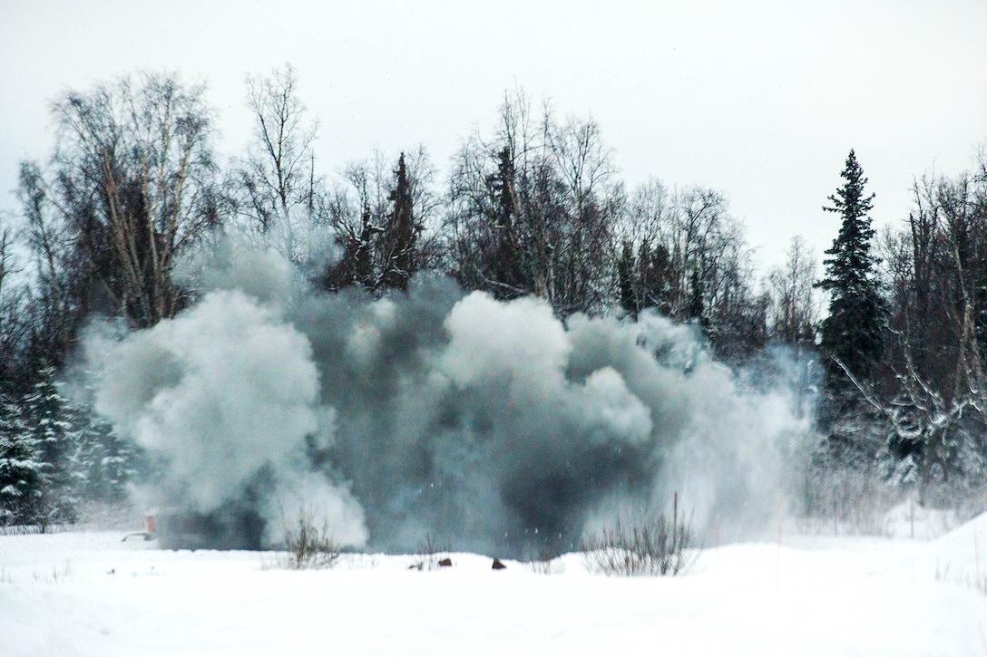 Explosive charges hurl snow and debris into the air during a live-fire demolitions exercise.