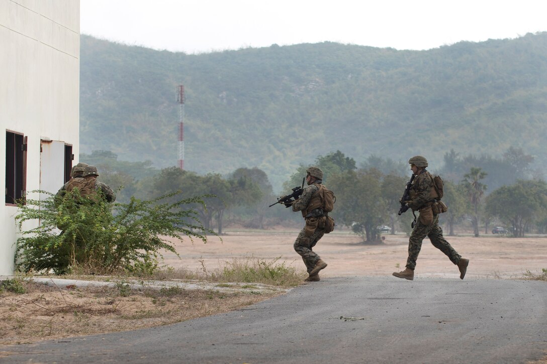 Marines cross a roadway to clear buildings during an amphibious assault.