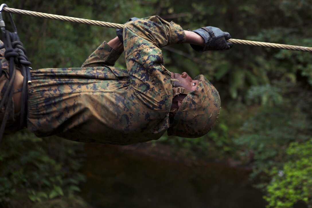 Marine Corps Lance Cpl. Daron Bush pulls himself across a cable obstacle during the Endurance Course.
