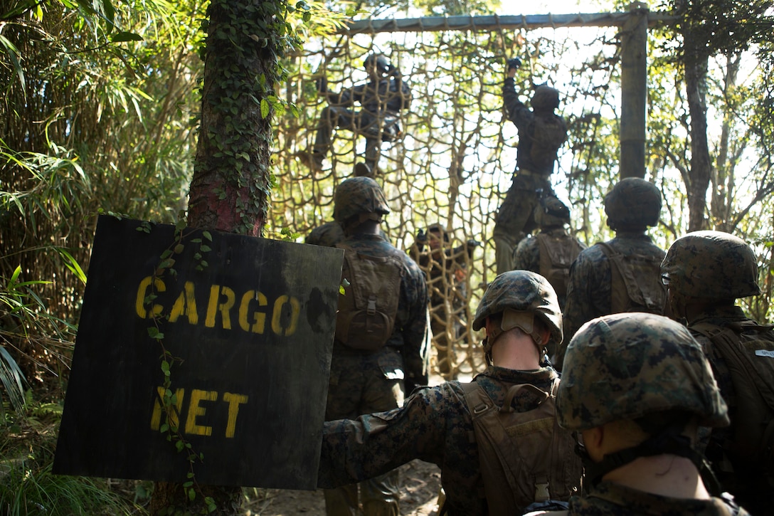 Marines climb over the cargo net obstacle during the Endurance Course.