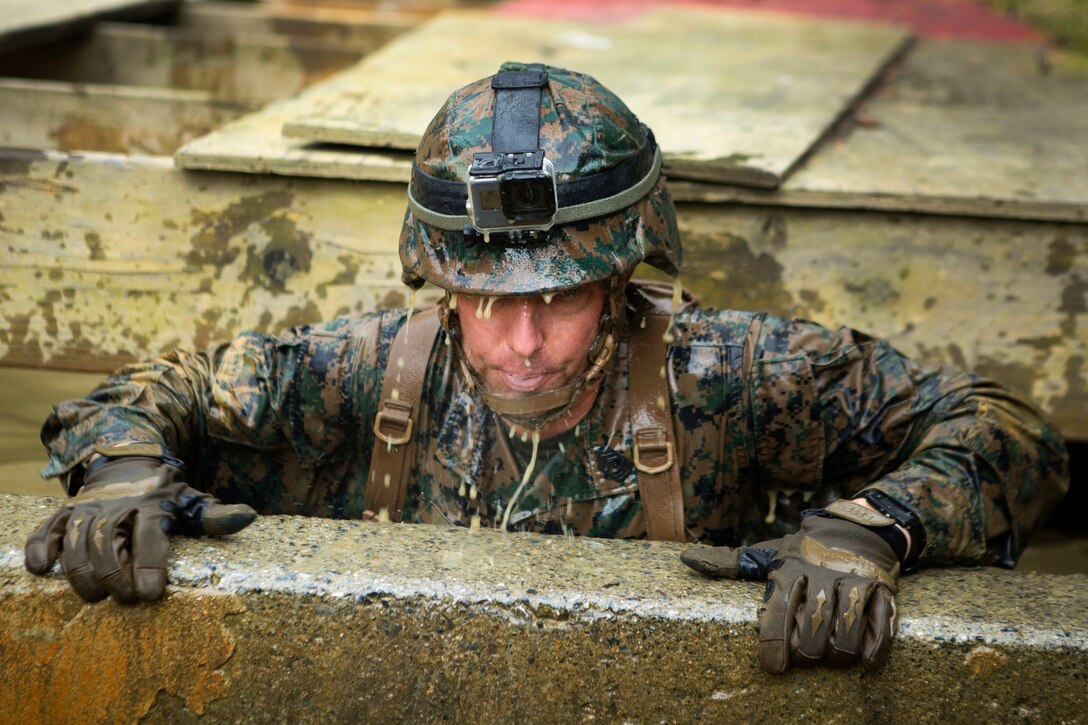 Marine Corps 1st Sgt. Thomas W. Tabisz lifts himself out of a muddy, water-filled pit during the Endurance Course.