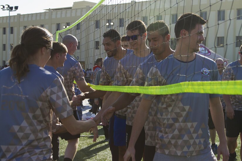 U.S. Soldiers and Sailors shake hands with Qatari service members after a volleyball game.