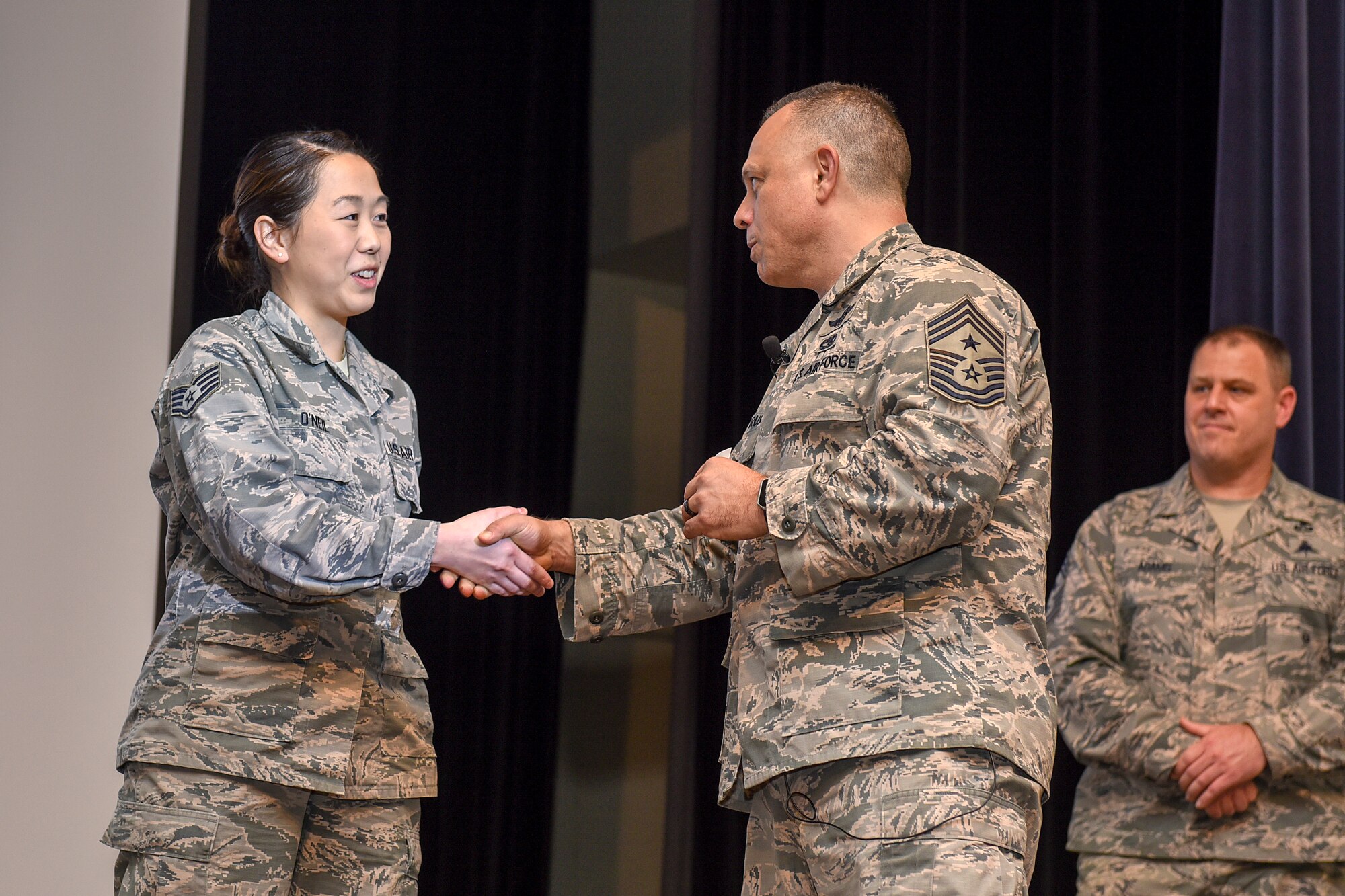 Chief Master Sgt. Matthew Caruso, command senior enlisted leader of U.S. Transportation Command, coins Staff Sgt. Heidi O'Neil, 4th Aircraft Maintenance Squadron personnel technician, for her outstanding performance during a senior NCO all call at the theater Feb. 15, 2018, at Seymour Johnson Air Force Base, North Carolina.