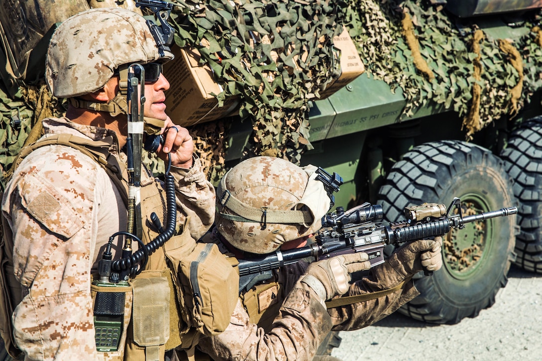 A Marine provides security for a noncommissioned officer using the radio.