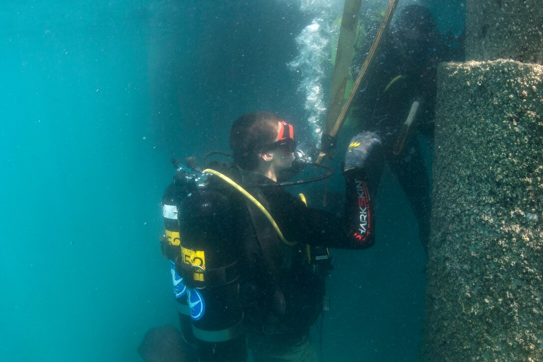 U.S. and Thai divers inspect a pile during a pier assessment.