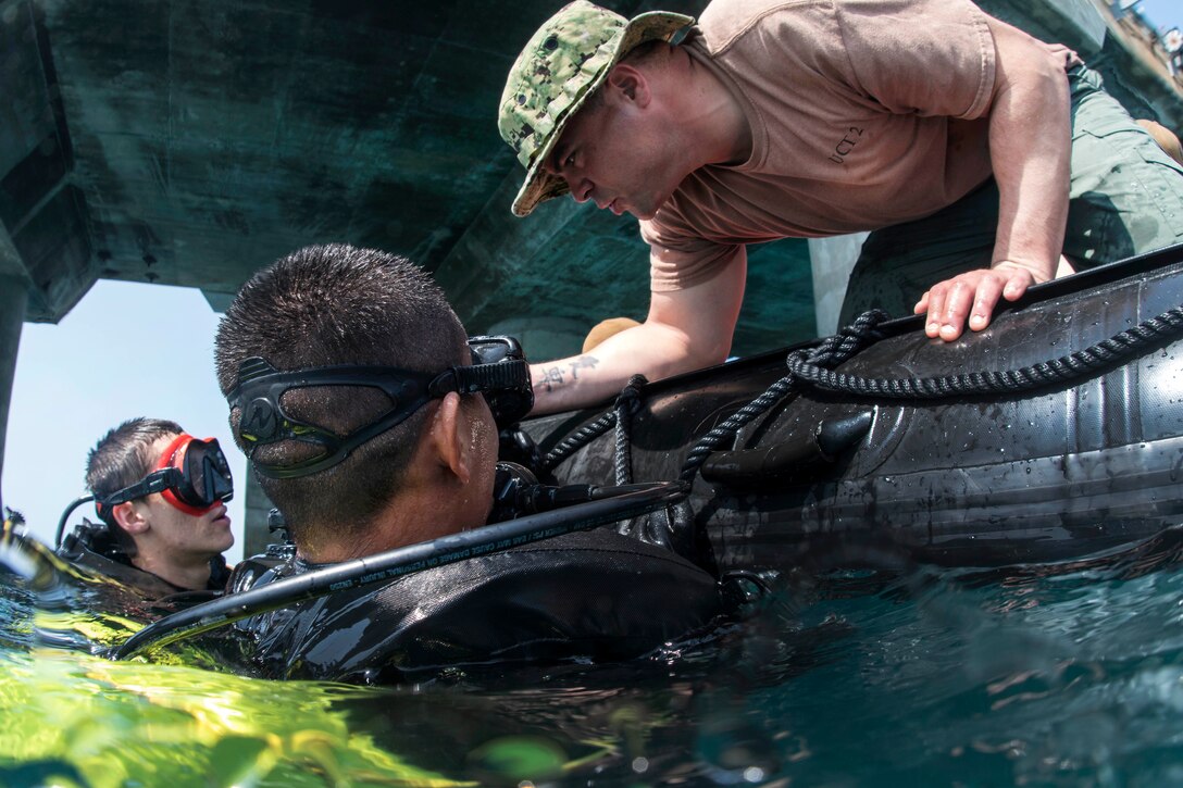 A Navy petty officer checks the bottle pressures for divers during a pier assessment.