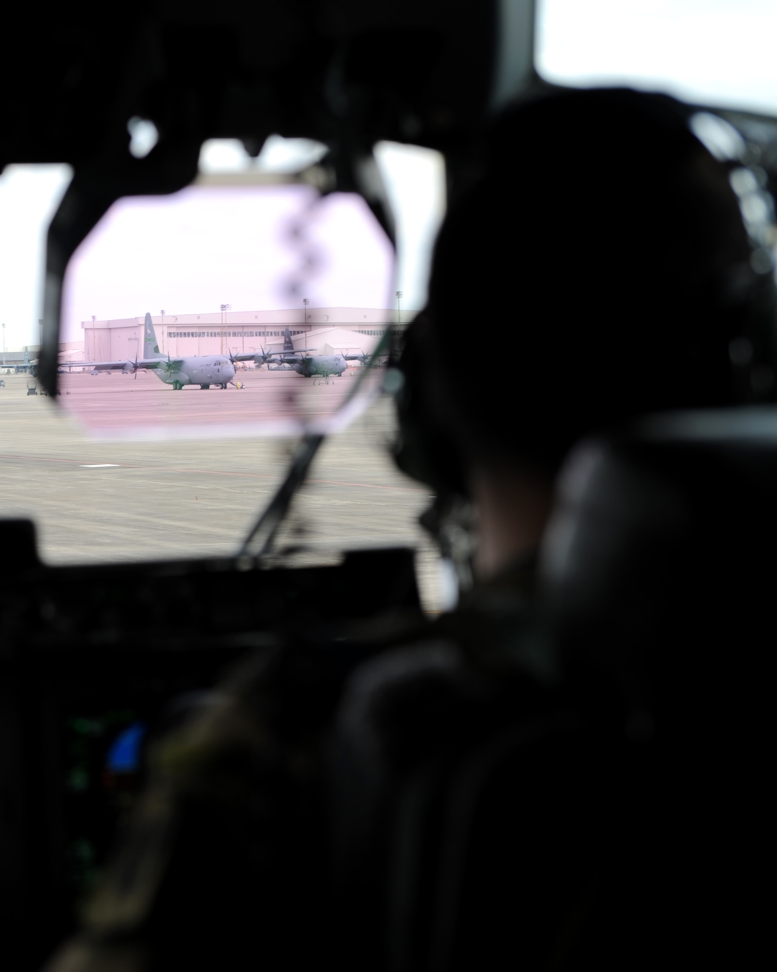 A rectangle photo with a male looking out an aircraft windshield at an aircraft.
