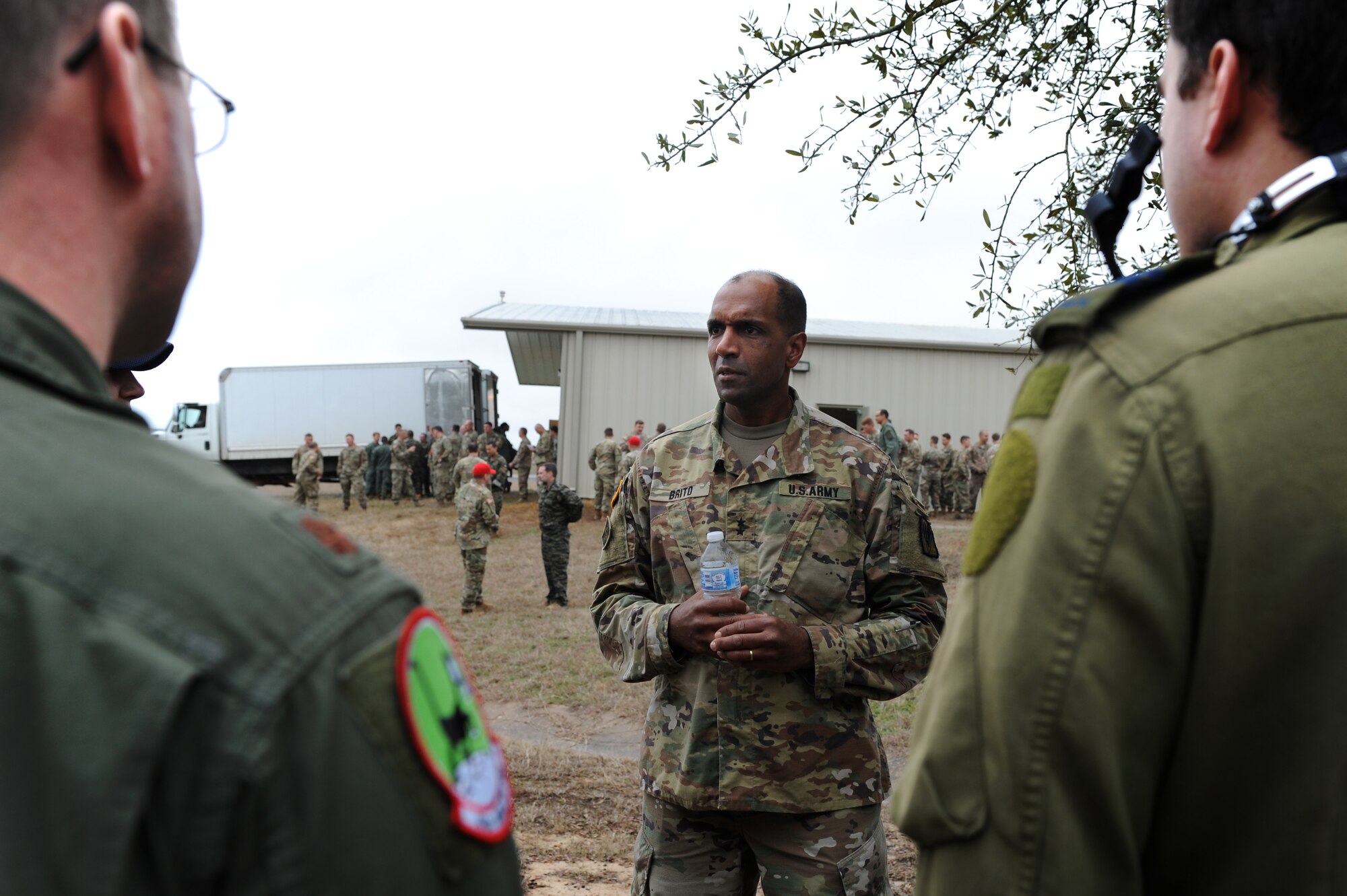 A square photo with two males in U.S. Air Force and Royal Canadian Air Force uniforms speaking to a male in a U.S. Army uniform.