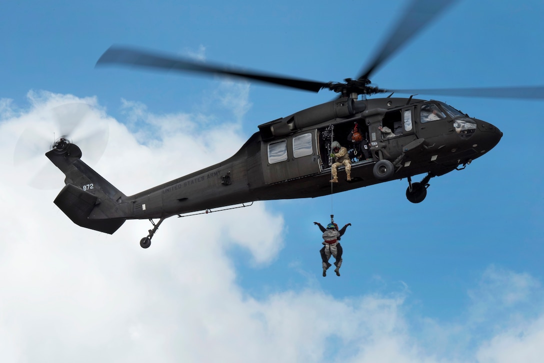 A person is lowered from a military helicopter.