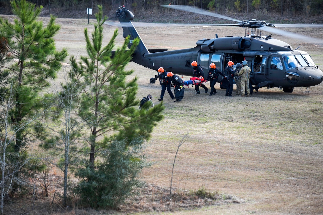 People carry a person on a stretcher away from a helicopter.