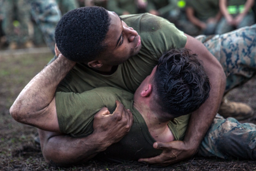 Two Marines grapple on a grassy field.