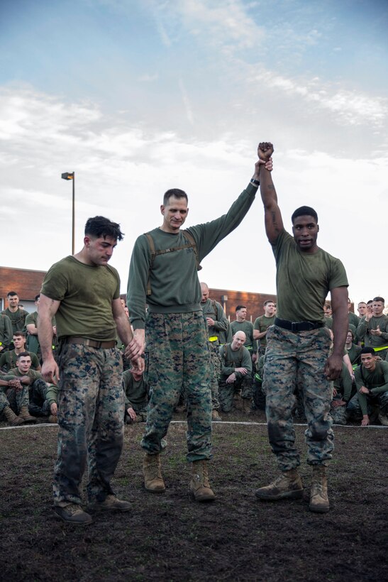 A Marine holds another Marine's arm up in the air.