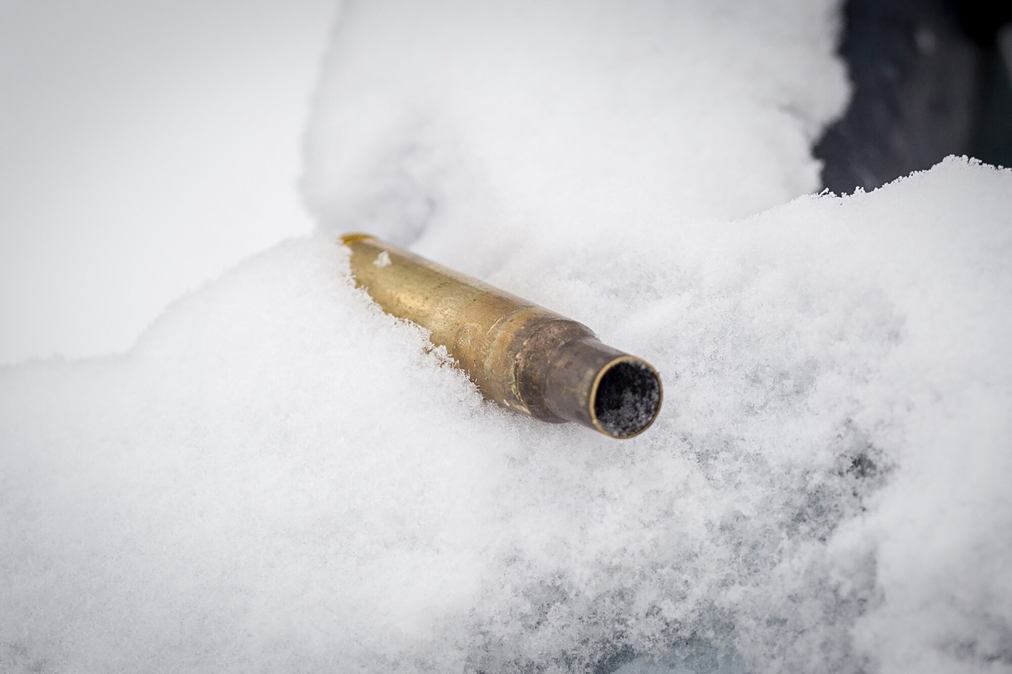 An expended .50 caliber machine gun casing is seen embeded in the snow as Soldiers assigned to the 1st Battalion, 5th Infantry Regiment, 1st Stryker Brigade Combat Team, 25th Infantry Division, U.S. Army Alaska, execute gunnery on Joint Base Elmendorf-Richardson, Alaska, during Operation Punch Bowl. The Fort Wainwright based Soldiers' operation culminated with multiple live-fire and combat training events.
