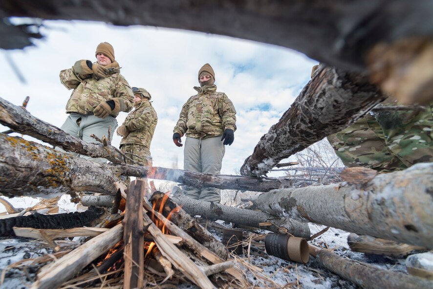 Defenders from the 91st Security Forces Group stand near a fire during a field training exercise in the Turtle Mountain State Forest, N.D., Feb. 14, 2018. After navigating to a landing zone, Airmen created a signal fire by adding grass to the burning brushwood. (U.S. Air Force photo by Senior Airman J.T. Armstrong)