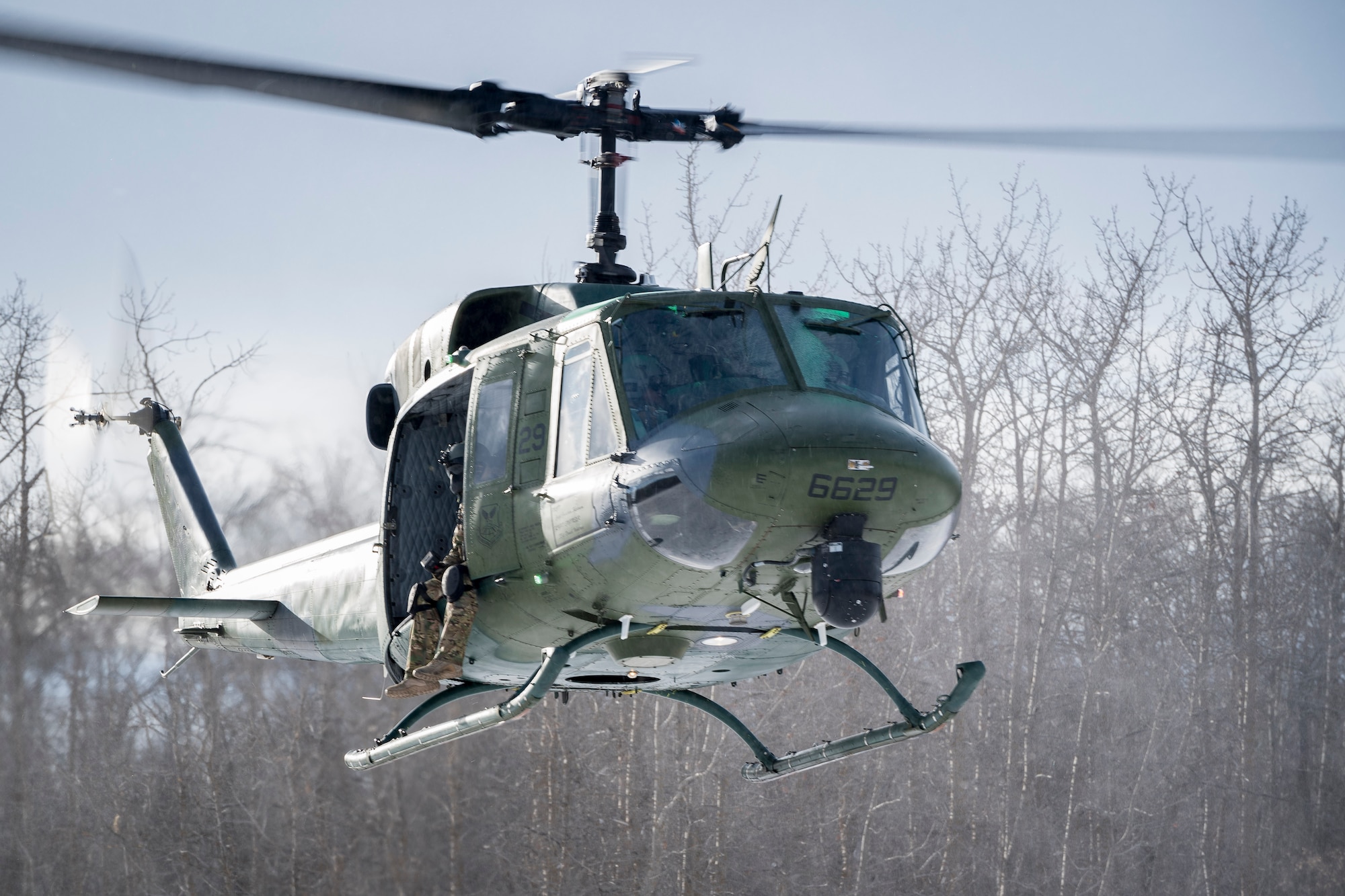 A 54th Helicopter Squadron UH-1N Iroquois hovers over the Turtle Mountain State Forest, N.D., Feb. 14, 2018, during a 91st Security Forces Group field training exercise. During the FTX, defenders vectored the aircraft to a landing zone and performed a simulated medical evacuation. (U.S. Air Force photo by Senior Airman J.T. Armstrong)