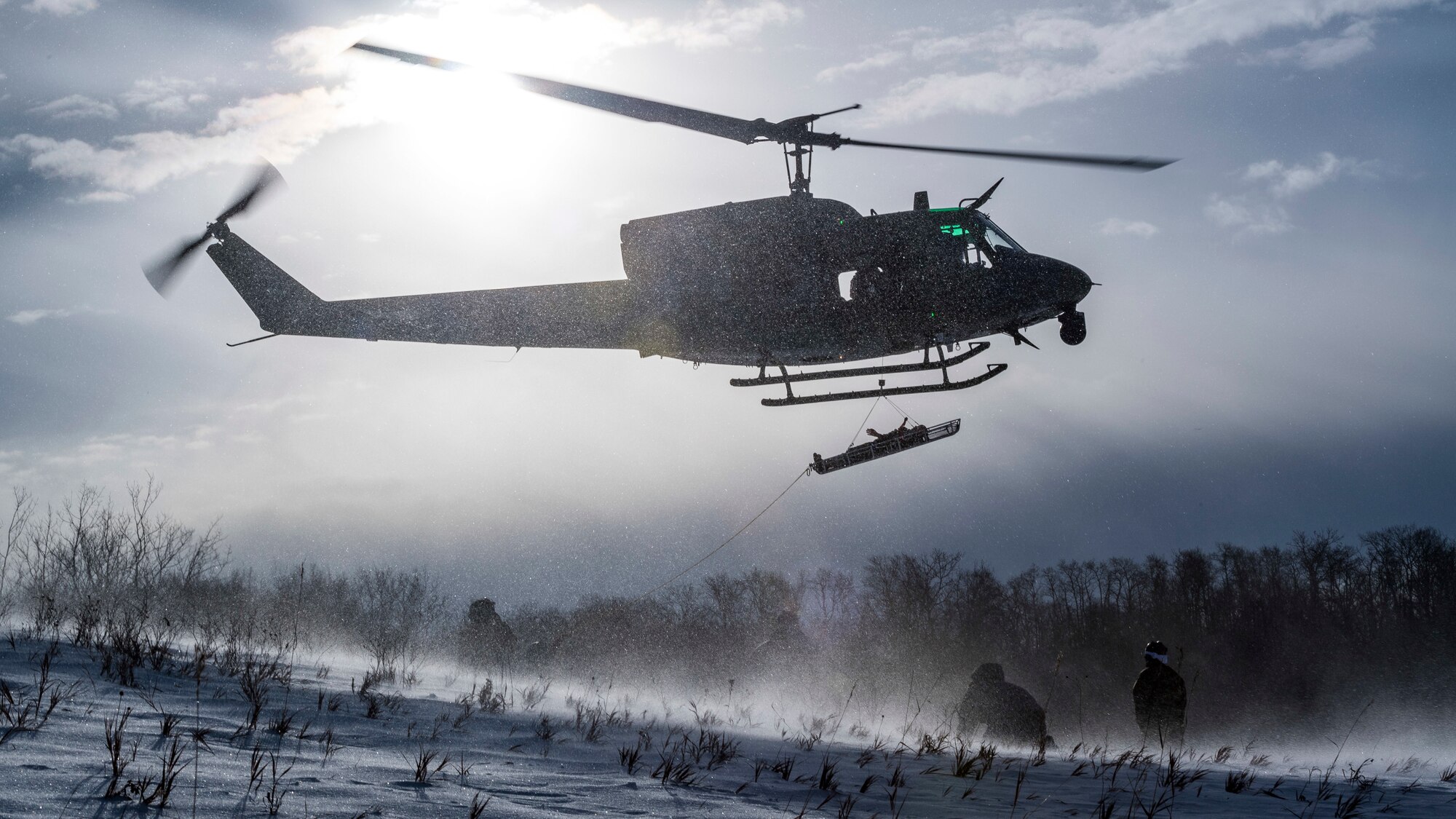 A UH-1N Iroquois assigned to the 54th Helicopter Squadron  lifts a simulated casualty above the Turtle Mountain State Forest, N.D., Feb. 14, 2018, during a 91st Security Forces Group field training exercise. During the FTX, defenders vectored the aircraft to a landing zone and performed a simulated medical evacuation. (U.S. Air Force photo by Senior Airman J.T. Armstrong)