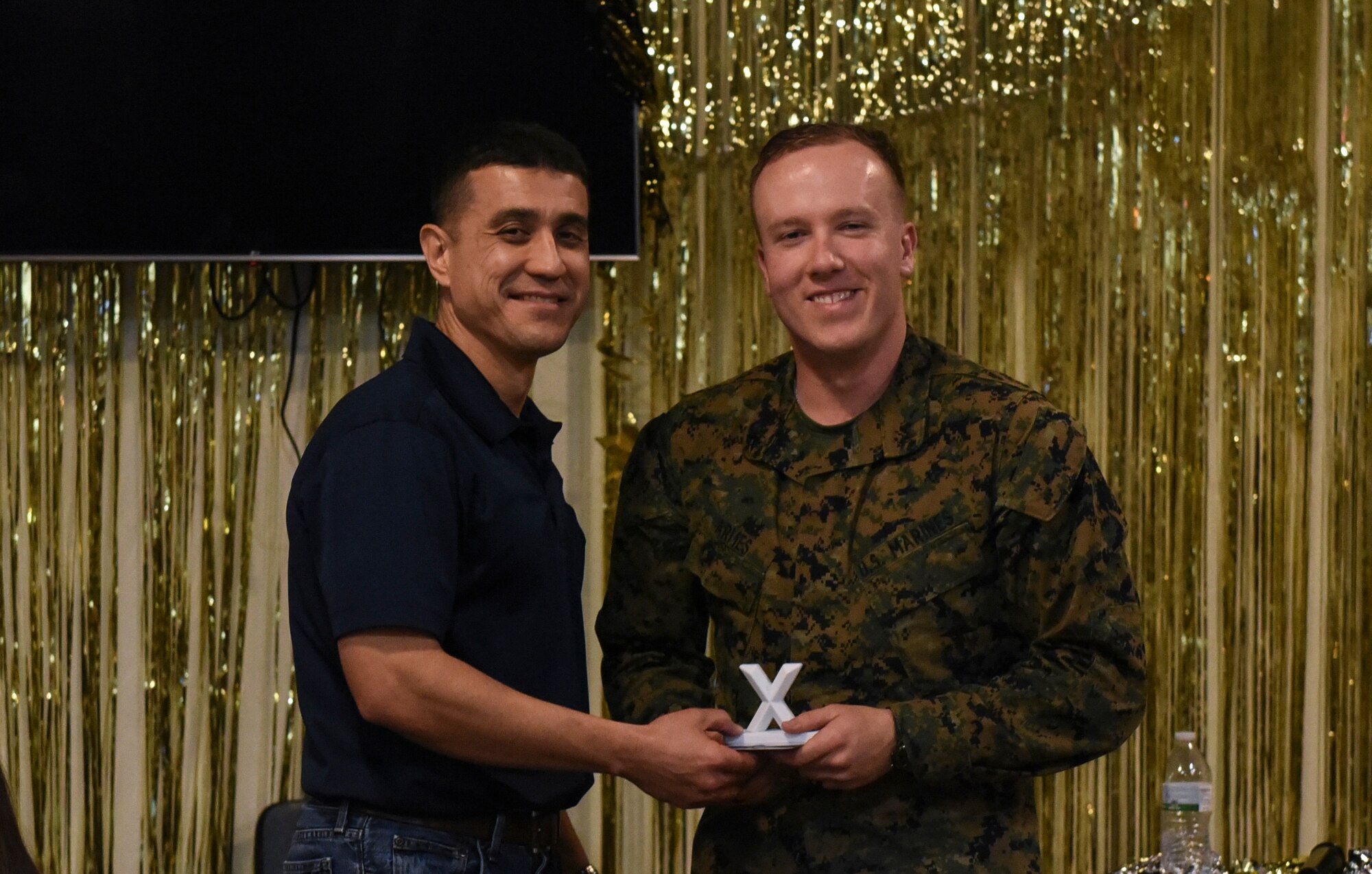 U.S. Air Force Col. Ricky Mills, 17th Training Wing commander, awards U.S. Marine Corps. Pfc. Jared Armes, Marine Corps Detachment trainee, with the 2nd place trophy during the 11th Annual Talent Show at the Crossroads on Goodfellow Air Force Base, Texas, Feb. 16, 2018. Armes played guitar and sang to an original song called ‘Wayside’. (U.S. Air Force Photo by Airman 1st Class Zachary Chapman/Released)