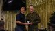 U.S. Air Force Col. Ricky Mills, 17th Training Wing commander, awards U.S. Marine Corps. Pfc. Connor Morgan, Marine Corps Detachment trainee, the 1st place trophy during the 11th Annual Talent Show at the Crossroads on Goodfellow Air Force Base, Texas, Feb. 16, 2018. Morgan received a standing ovation for his guitar solo that won him the 1st place spot. (U.S. Air Force Photo by Airman 1st Class Zachary Chapman/Released)