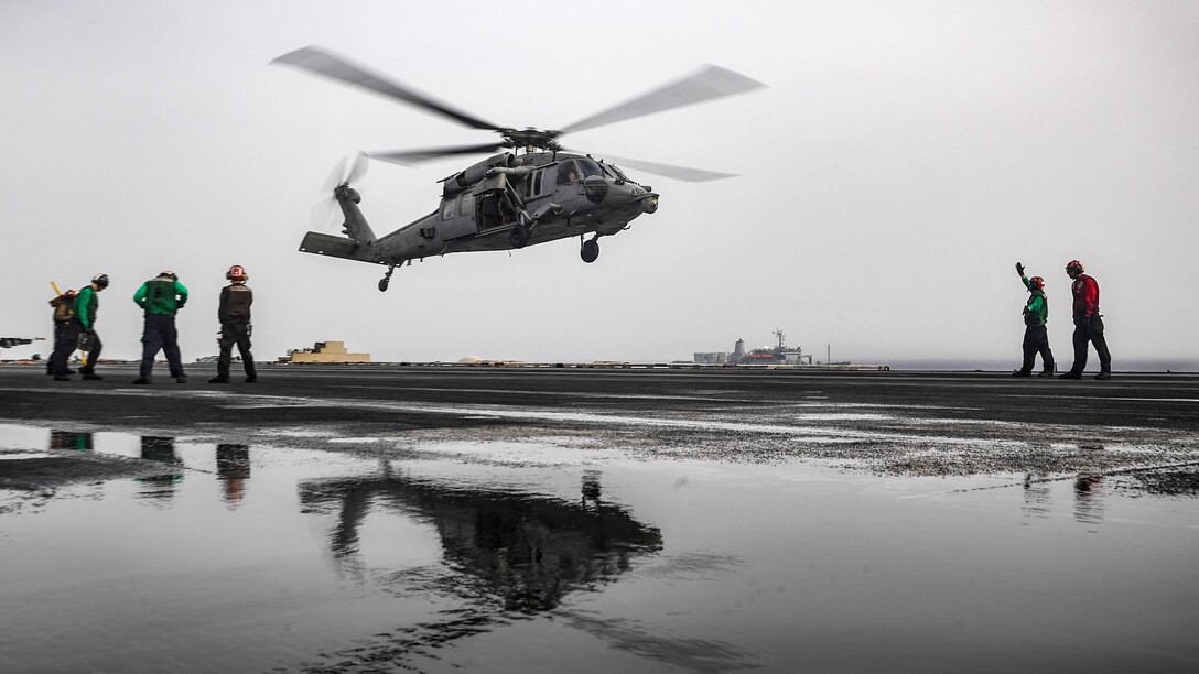 A Seahawk helicopter prepares to land on a ship's flight deck.
