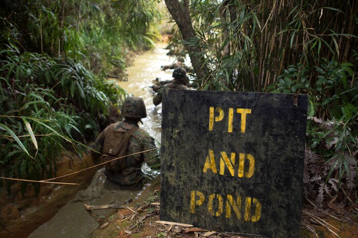 Marines begin their descent into a muddy water obstacle.