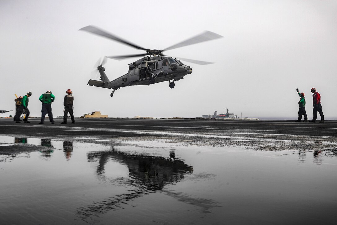 A Seahawk helicopter prepares to land on a ship's flight deck.