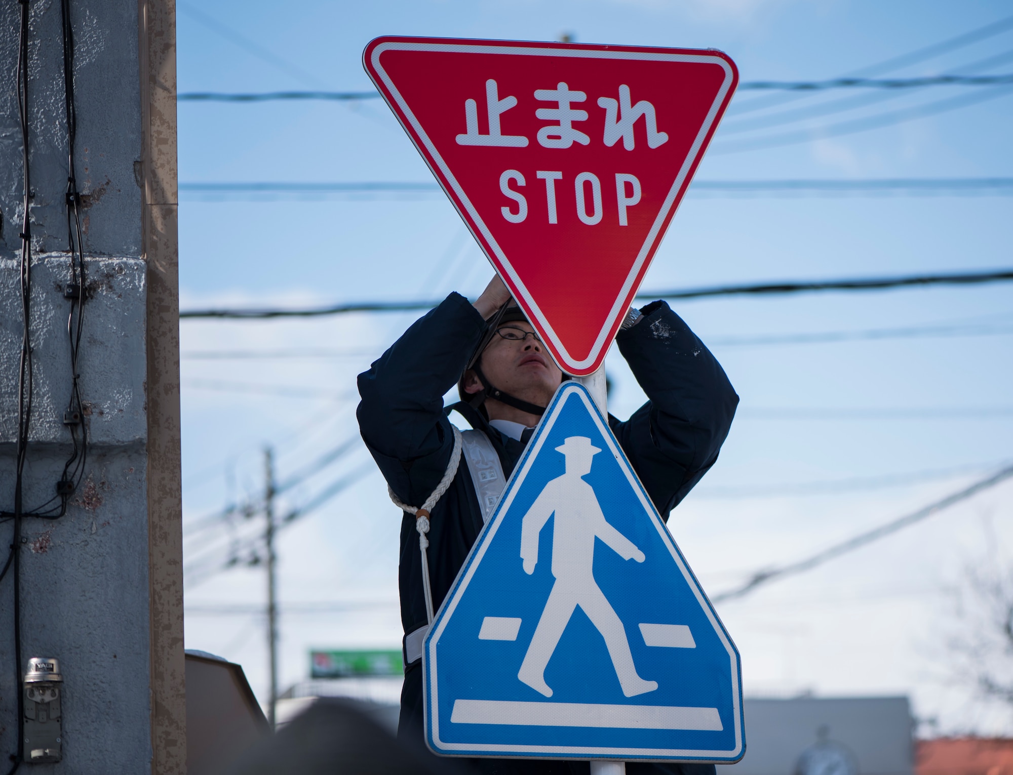 A Misawa City Police officer installs a stop sign at an intersection in Misawa City, Japan, Feb. 15, 2018. The installation of a bi-lingual stop signs is not only beneficial to driver safety but is a quick process that takes less than five minutes to complete. (U.S. Air Force photo by Airman 1st Class Collette Brooks)