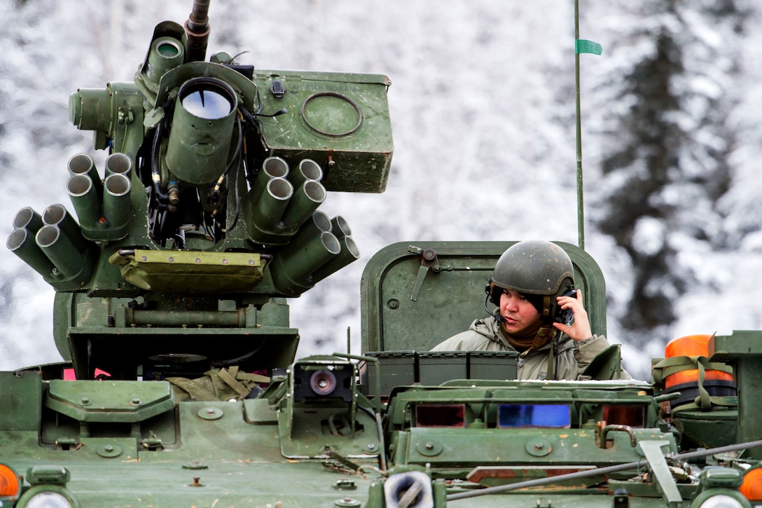 A soldier relays information via radio while in a Stryker armored vehicle.