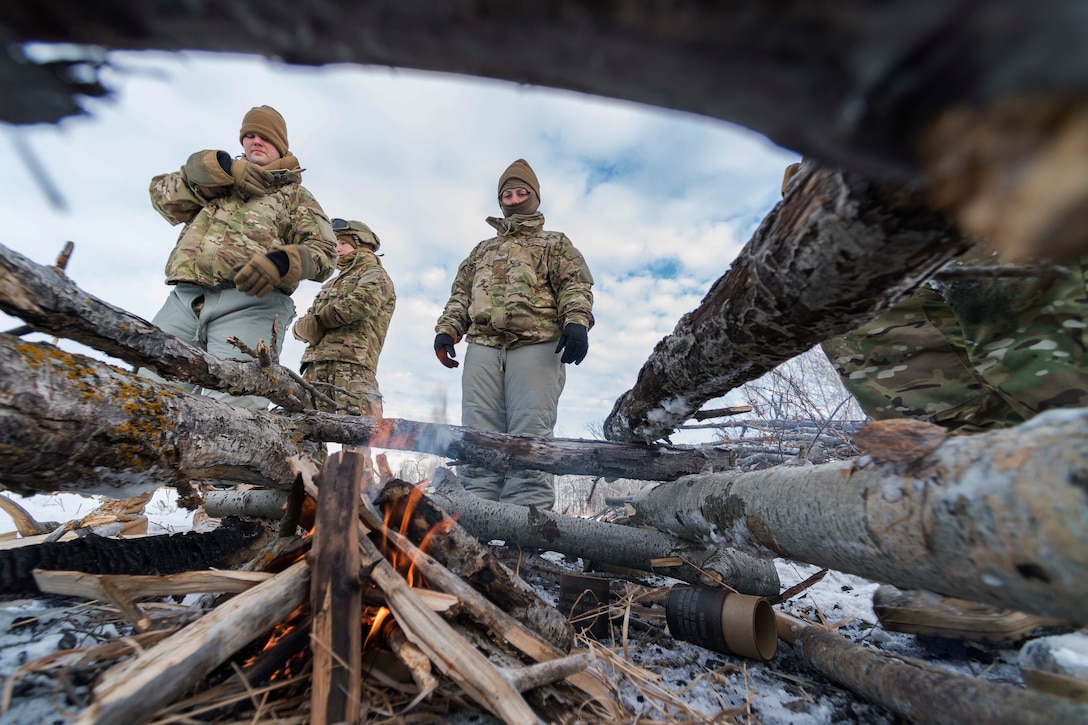 Airman assigned to the 91st Security Forces Group stand near a fire.