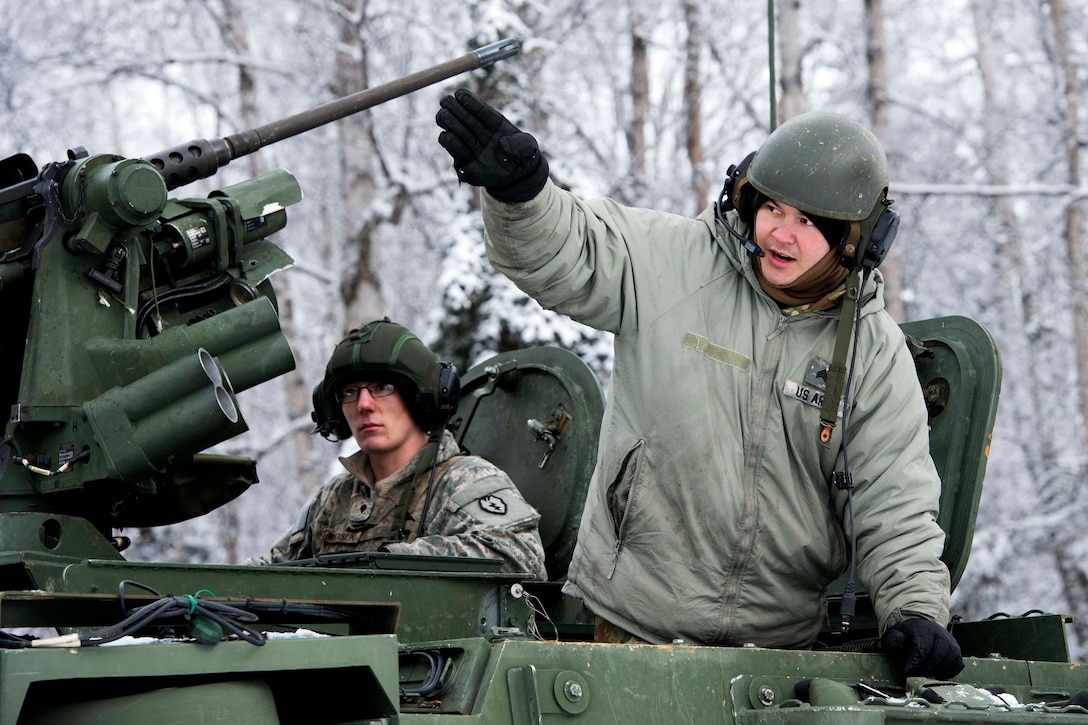 A soldier in a Stryker armored vehicle makes a hand signal.