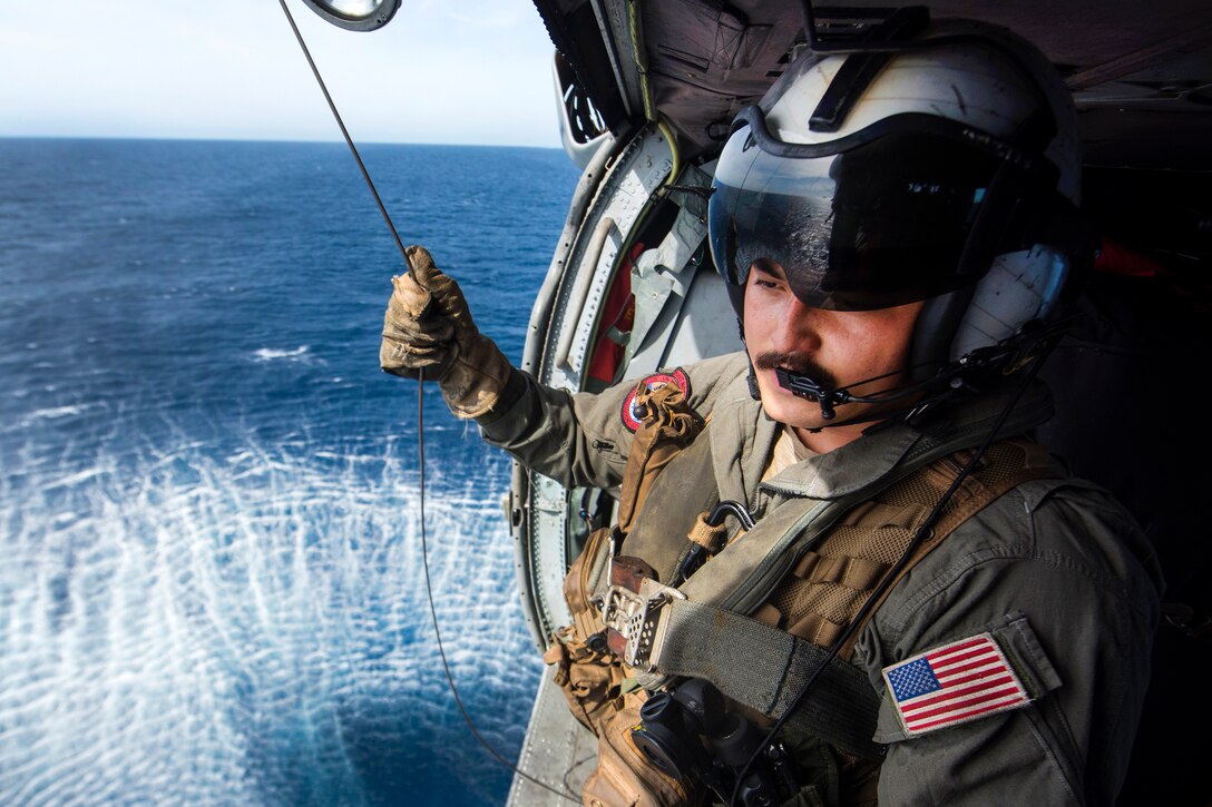 Navy Petty Officer 2nd Class Sebastian Mendieta serves as crew chief inside an MH-60S Sea Hawk helicopter during a search and rescue exercise.