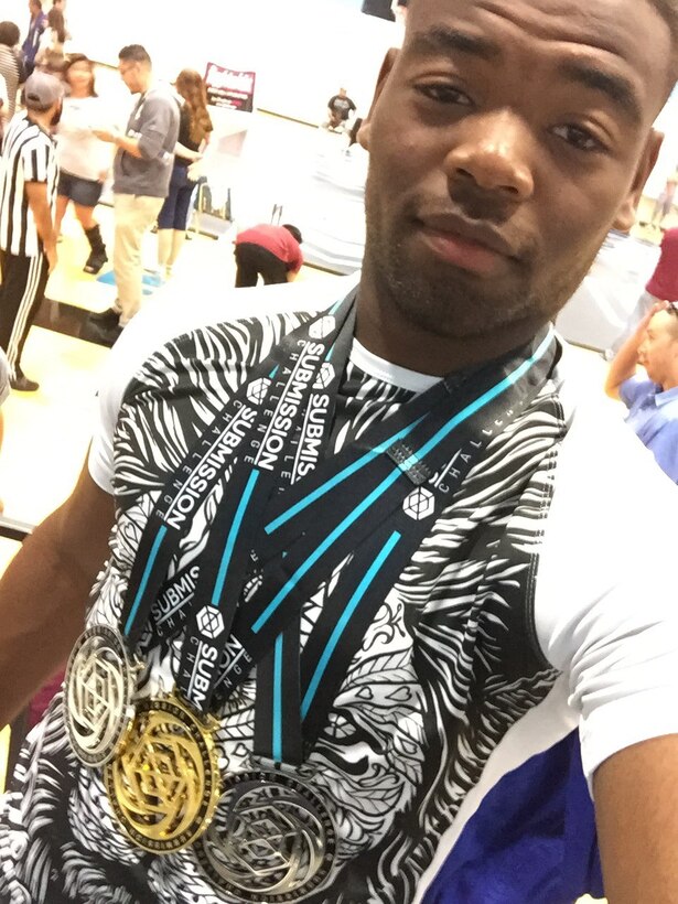 Senior Airman Paul Buchanan, 94th Aircraft Maintenance Squadron avionics technician, takes a picture wearing various medals he won during a Brazilian Jiu Jitsu competition. Buchanan helps coach a kids Brazilian Jiu Jitsu class and recently signed his first professional contract as a mixed martial arts fighter. (Courtesy photo/Senior Airman Paul Buchanan)