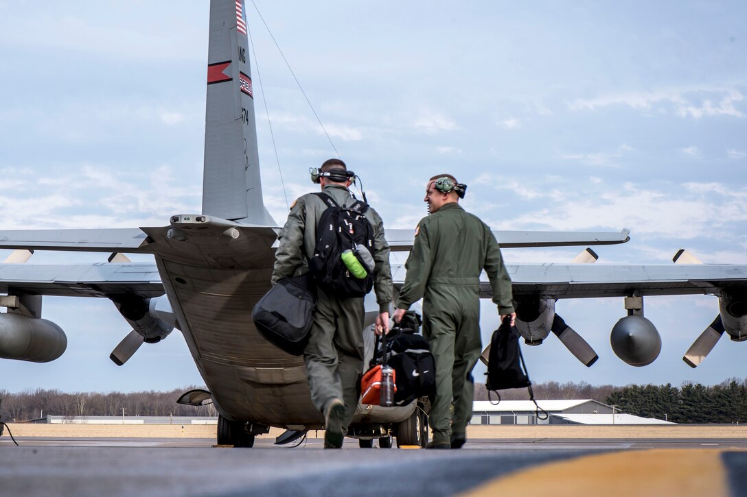 Air Force Master Sgt. Robert Snyder and Staff Sgt. Spencer Magers carry their gear before boarding a C-130H Hercules aircraft.