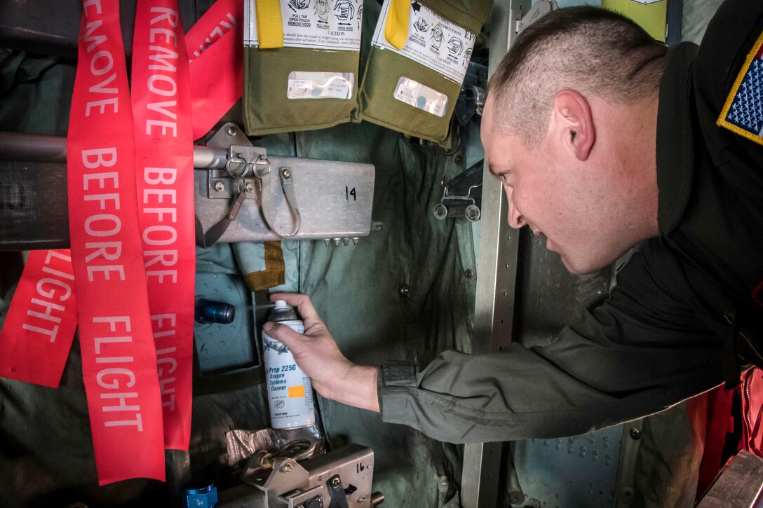 Air Force Master Sgt. Robert Snyder cleans and inspects an oxygen systems valve using an ultra violet light to highlight any debris.