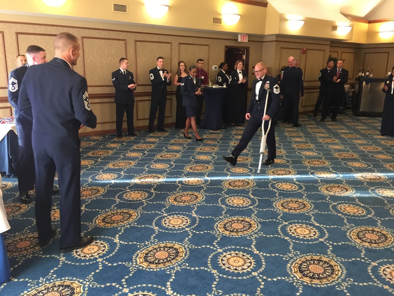 Then Senior Master Sgt. Chad Caden, the chief enlisted manager with the 633rd Civil Engineer Squadron at Joint Base Langley-Eustis, relies on a crutch during his Chief Induction ceremony in Hampton, Va., February 2017, nearly 2 months after receiving an amputation on his right leg due to a bone disease called Osteonecrosis. Osteonecrosis caused Caden’s foot to lose blood flow and resulted in bone decay. This bone disease went undiagnosed for years while Caden experienced debilitating pain that significantly impacted his ability to work. (Courtesy  photo)