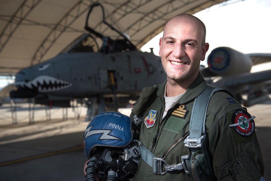 An Italian airman stands in front of an aircraft.