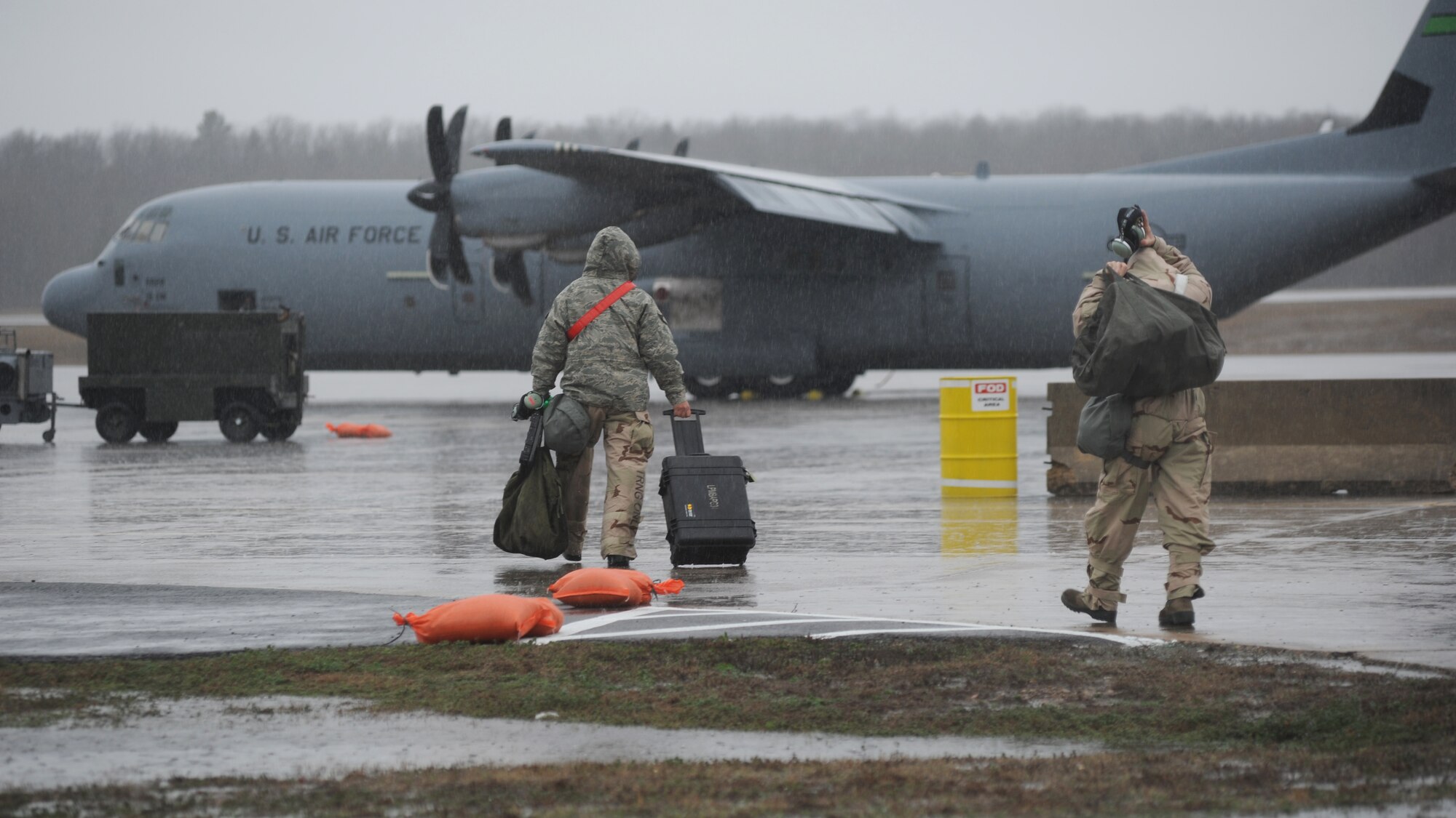 Two males are pictured walking toward an aircraft in the rain.