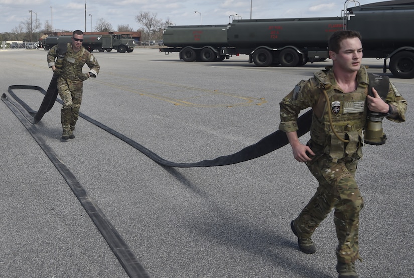 Tech. Sgt. Nicholas T. Piper, left, 628th Logistics Readiness Squadron Forward Area Refueling Point team chief and Senior Airman Christopher Stuebbe, right, 628th Logistics Readiness Squadron fuels distribution supervisor run with fuel hoses as part of a demonstration during a FARP team tryout Feb. 15, 2018.