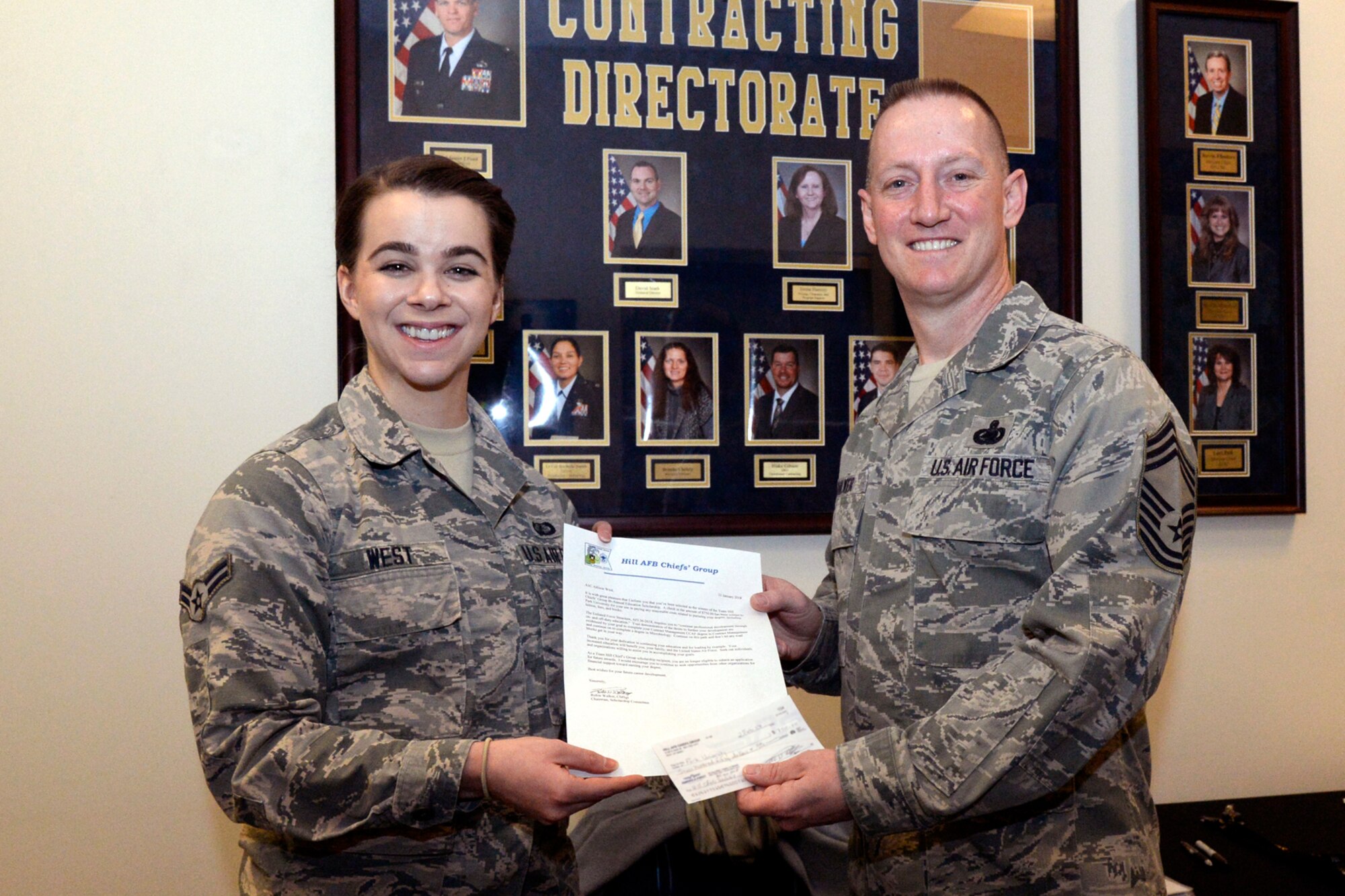 Airman 1st Class Allison West, Contracting Directorate, receives a $750 scholarship from Chief Master Sgt. Rulon Walker, representing the Chiefs' Group, at Hill Air Force Base, Utah, Feb. 15, 2018. (U.S. Air Force photo by Todd Cromar)