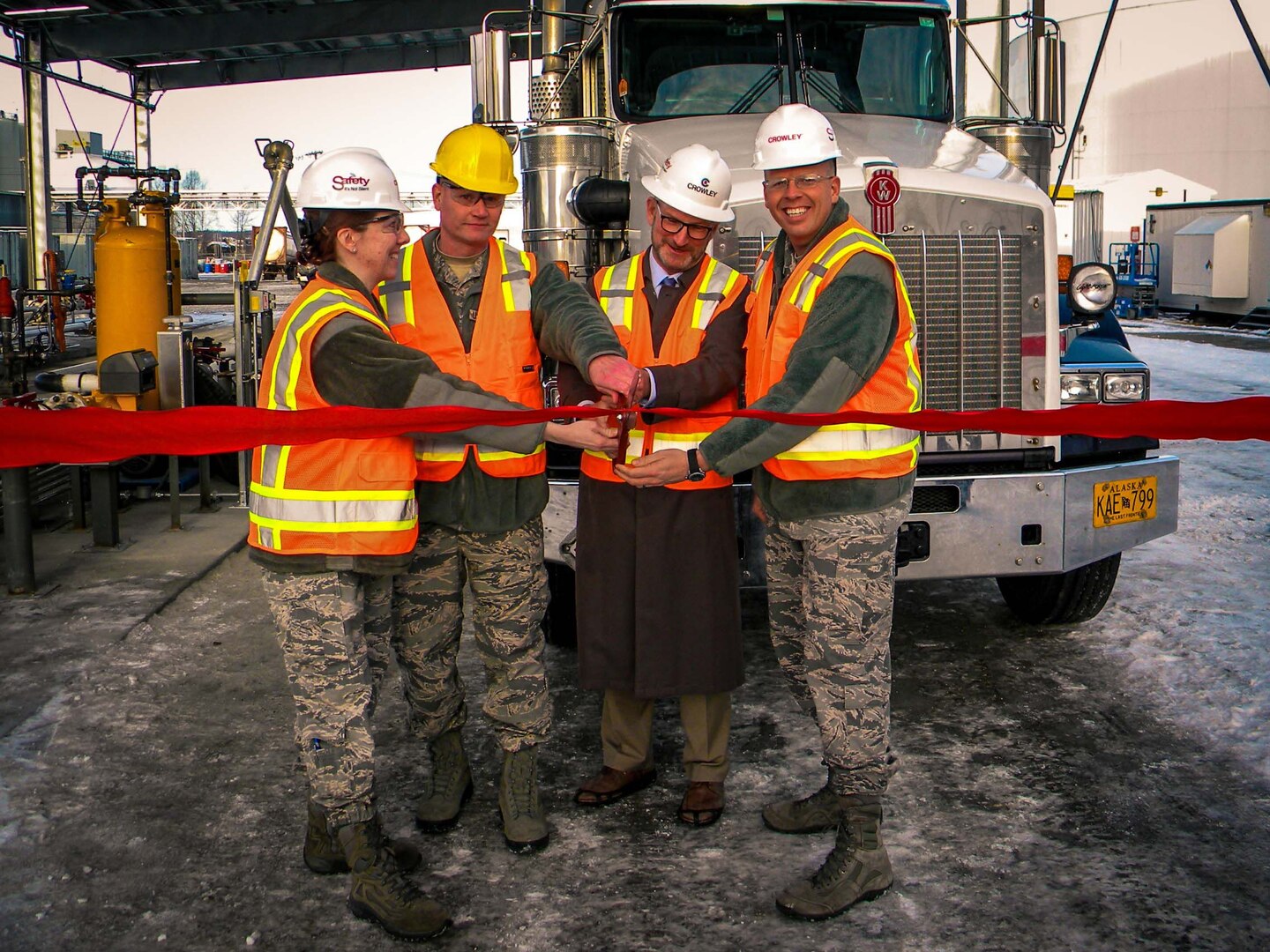 Four individuals cut a ceremonial ribbon for the opening of a new tank truck fueling station.