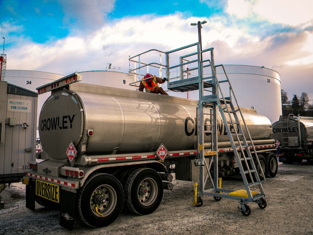 A quality assurance representative inspects a tank truck compartments during a pre-fuel inspection.