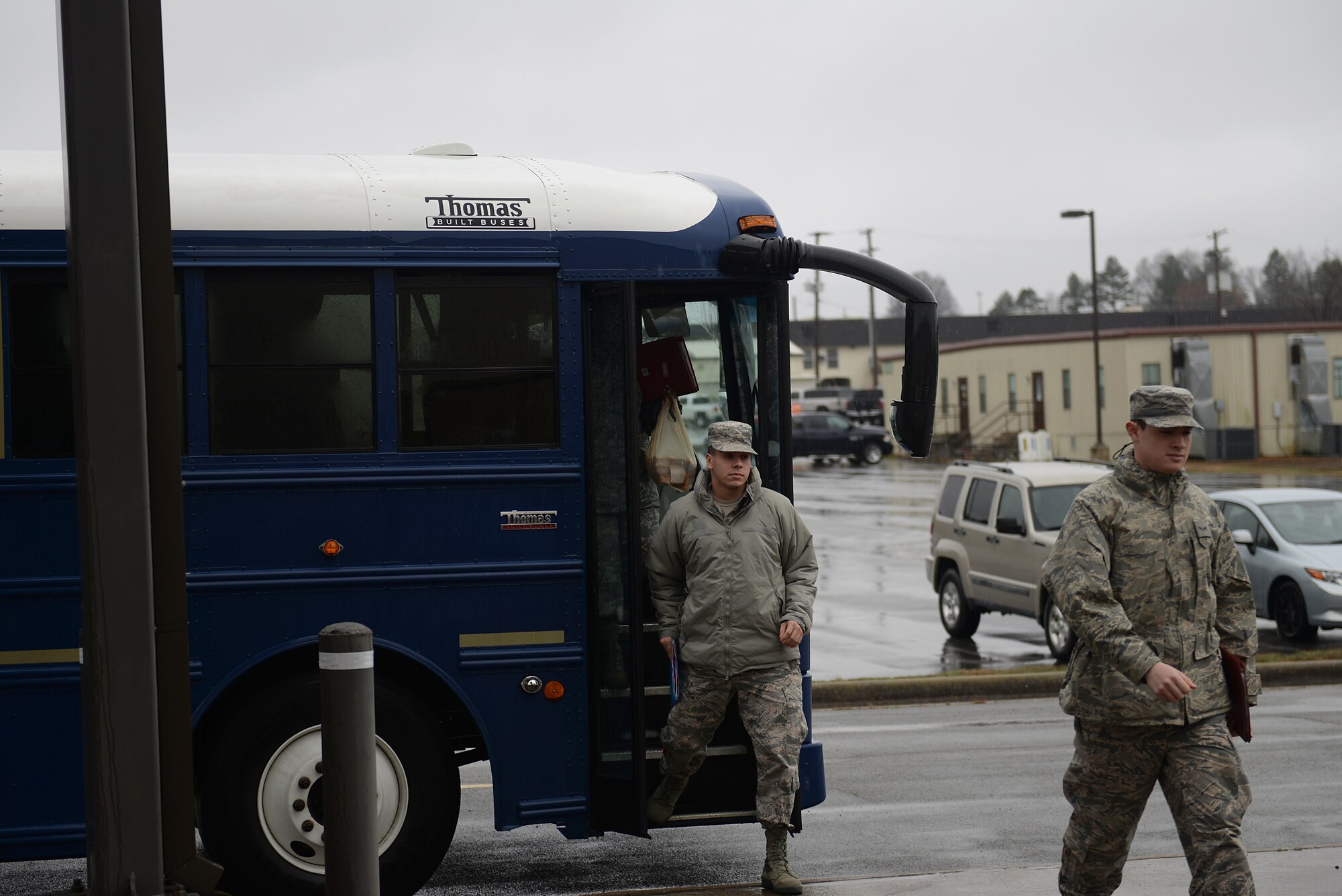 Three Airmen in Air Force Battle Uniforms walk off a bus.