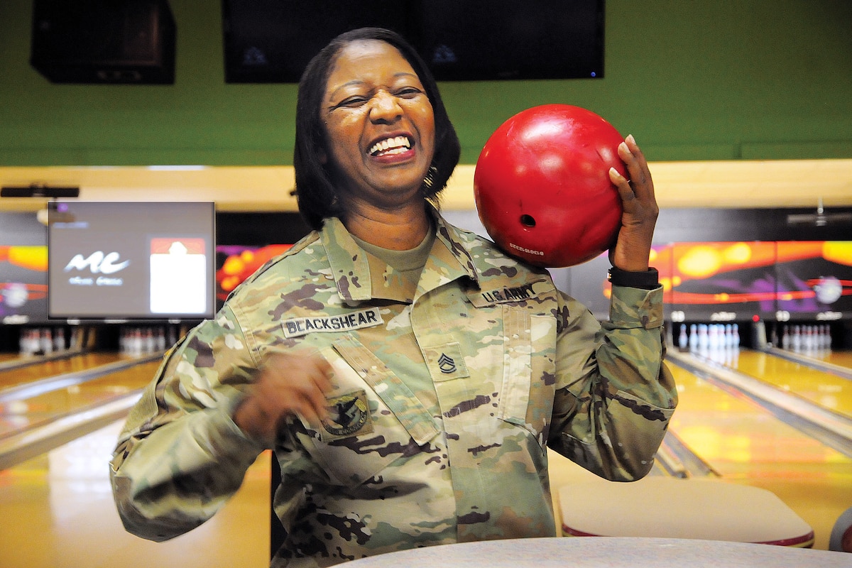 A soldier holds a bowling ball.