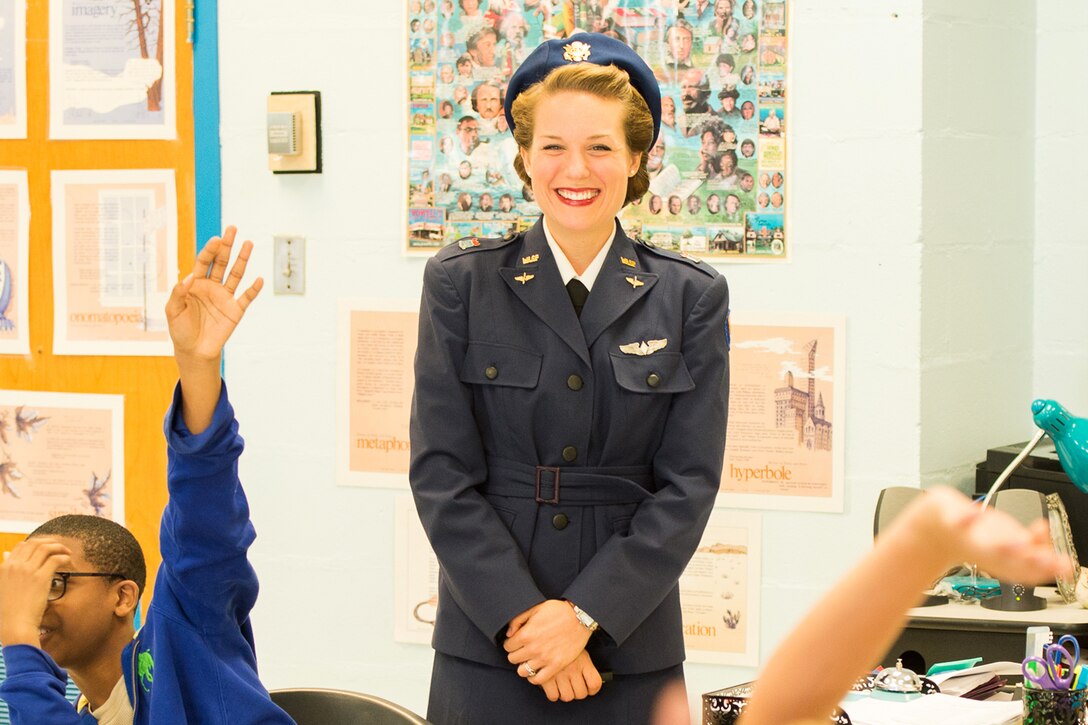 A woman dressed in a Women's Air Force Service Pilot uniform stands in front of a class.
